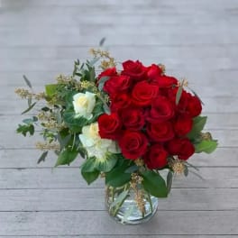 Red roses and white blooms arranged in a clear glass vase