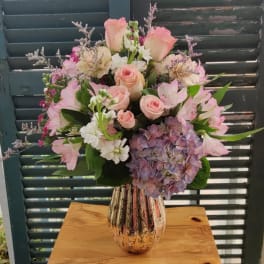 Pink roses and hydrangeas arranged in a striped ceramic vase