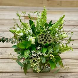 Green floral arrangement with white blooms in a glass vase