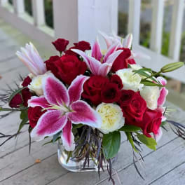 Red roses and pink lilies arranged in a clear glass vase