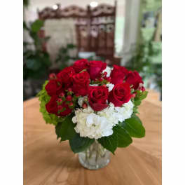 Red roses and white hydrangeas arranged in a clear glass vase