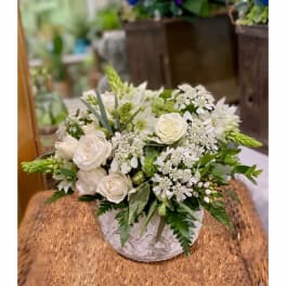 White rose and mixed white flower arrangement in a white vase