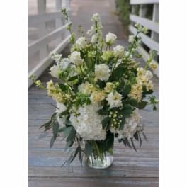 White and pale yellow floral arrangement in a clear glass vase