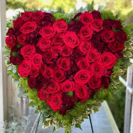 Heart-shaped arrangement of red roses with green foliage