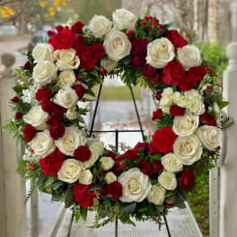 Circular wreath of red and white roses on a black stand