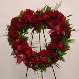 Heart-shaped floral wreath with red roses and pink lilies on a stand