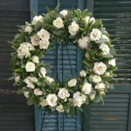 White floral wreath on a black metal stand