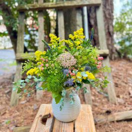 Wildflower bouquet in a white vase with yellow and pink blooms