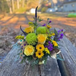 Yellow and purple mixed flower arrangement in a small vase