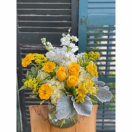 Yellow and white flower arrangement in a clear glass vase
