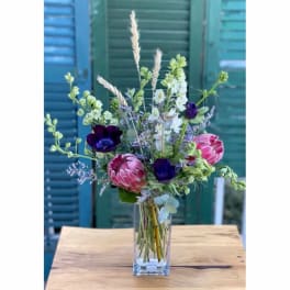 Tall mixed bouquet in a clear glass vase with pink and purple blooms