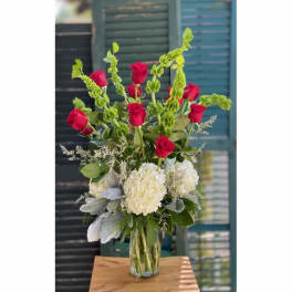 Tall bouquet of red roses and white hydrangeas in a clear glass vase