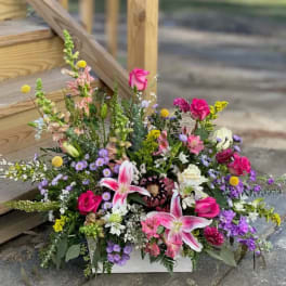 Large mixed flower arrangement in a white box with pink lilies and roses