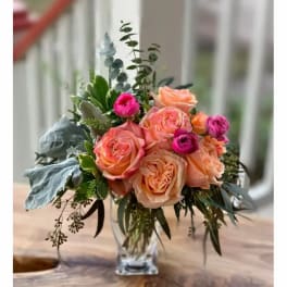 Peach and pink roses arranged in a clear glass vase