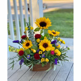 Mixed bouquet with sunflowers, yellow roses, and purple flowers in a basket