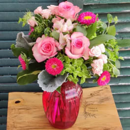 Pink roses and mixed blooms in a red glass vase