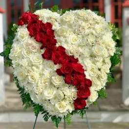 Heart-shaped floral tribute with red and white roses on a stand