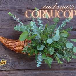 Wicker cornucopia filled with assorted greenery on a wood background