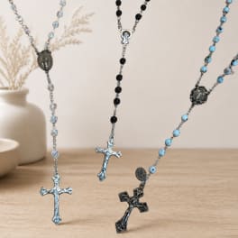 Rosary necklaces with beaded chains and metal crosses on a tabletop