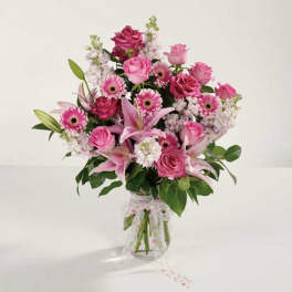 Pink mixed bouquet in a clear glass vase with a sheer ribbon
