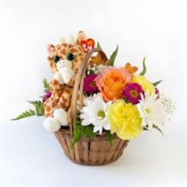 Basket of mixed flowers with a plush giraffe toy