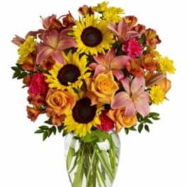 Bouquet of sunflowers, roses, and lilies in a clear glass vase