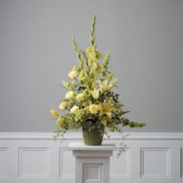 Tall yellow floral arrangement in a green vase on a pedestal