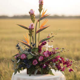 Tropical floral arrangement with pink roses and bird-of-paradise blooms in a low container