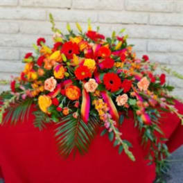 Bright mixed flower arrangement with red, orange, and yellow blooms in a low display