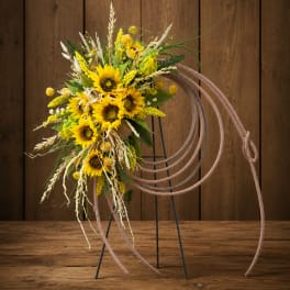 Sunflower arrangement with wheat accents on a decorative hoop stand