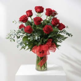 Red roses in a clear glass vase with a red ribbon