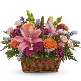 Mixed bouquet in a wicker basket with pink lilies, roses, and carnations