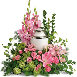 Pink flowers arranged around a white urn with silver trim