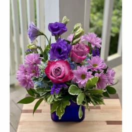 Purple and pink flower arrangement in a blue vase