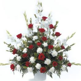 Red roses and white flowers arranged in a tall white vase