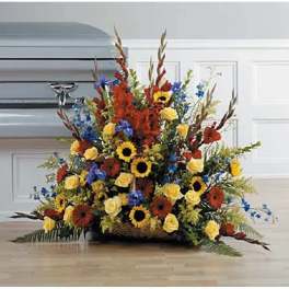 Large mixed flower arrangement with sunflowers, roses, and blue accents in a basket