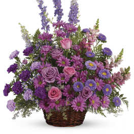 Purple and pink mixed flower arrangement in a wicker basket