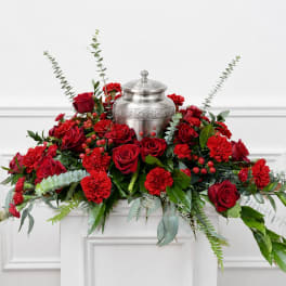 Red roses and carnations arranged around a silver urn
