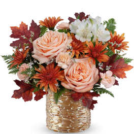 Peach roses and orange daisies in a gold vase with autumn leaves