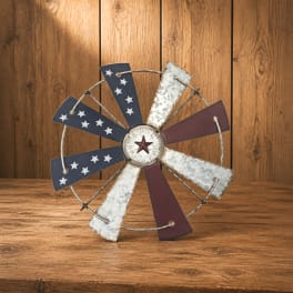 Decorative metal windmill-style wall art with stars in red, white, and blue