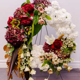 Large floral wreath with red, white, and pink blooms on a stand