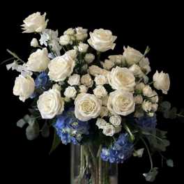 White roses and blue hydrangeas in a clear glass vase