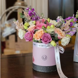 Pink and peach roses in a round gift box with a ribbon