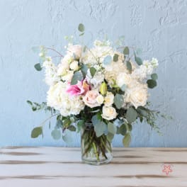 White and blush floral arrangement in a glass vase