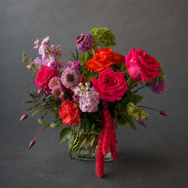 Mixed bouquet of pink, orange, and purple flowers in a glass vase