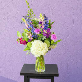 Mixed bouquet in a clear glass vase with white hydrangea and purple-blue flowers