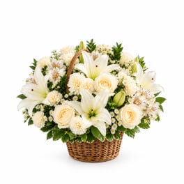 Cream flower arrangement in a wicker basket with lilies and roses