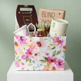 Gift basket with tea, a succulent, and packaged treats in a floral box