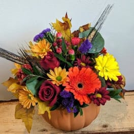 Mixed autumn bouquet in a pumpkin-shaped container with bright flowers