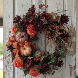 Fall wreath with orange roses, dark flowers, pumpkins, and plaid ribbon